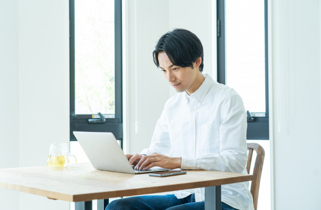 パソコンで業者を調べている男性