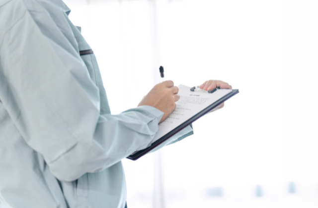 作業着姿でメモを取る人